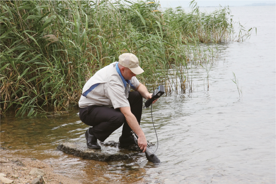 Man taking measurements at the water's edge using the Horiba U50 device.